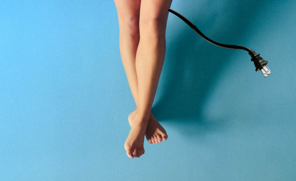 Bare legs, one attached to an unplugged electrical cord.